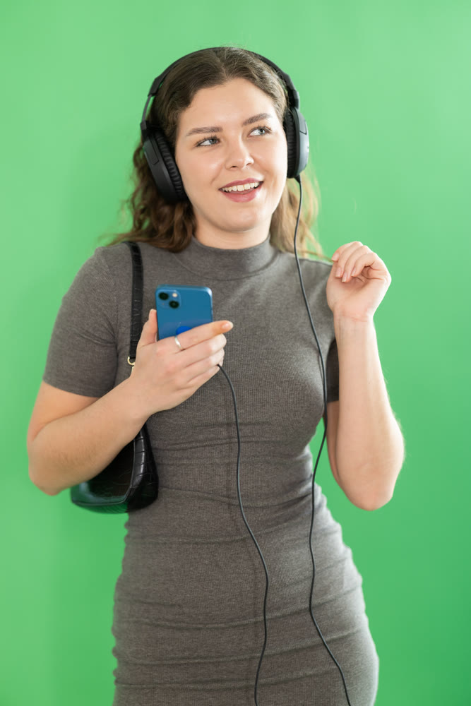 Girl listens to music using wired headphones and mobile phone