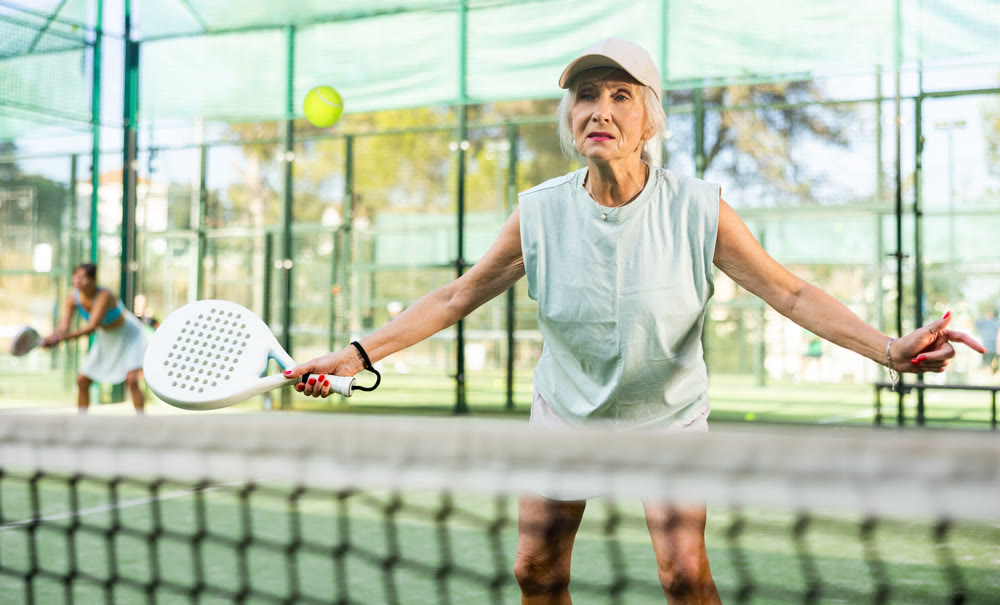Mature woman playing padel tennis on court