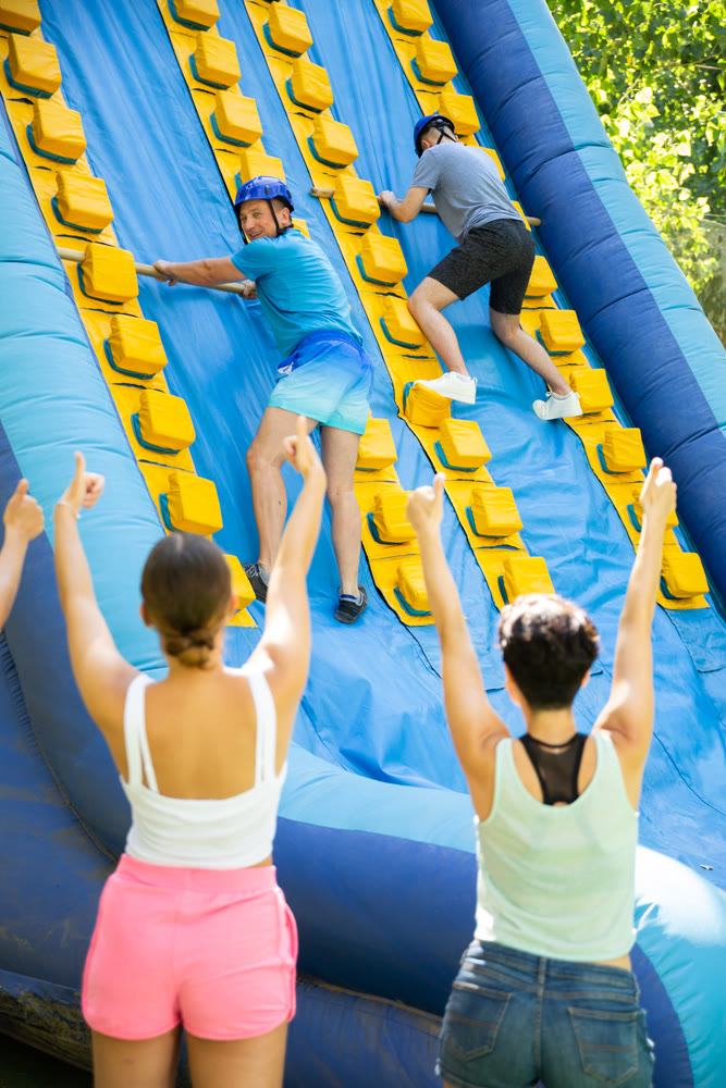 Father and son trying to climb on top of slide in amusement park