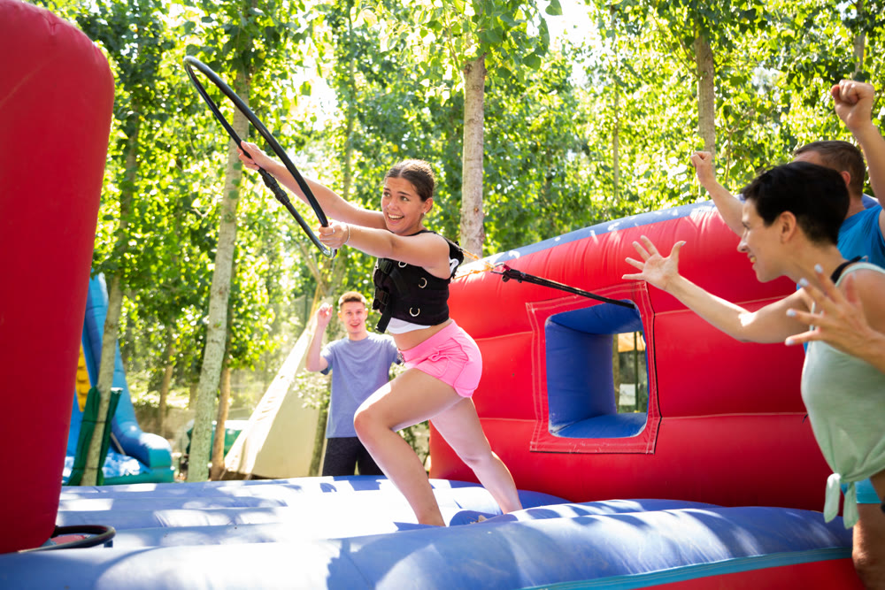 Happy young woman competing with friends in collect hoops on inflatable arena