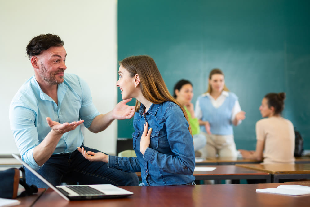 Students of university chatting on break sitting at desks