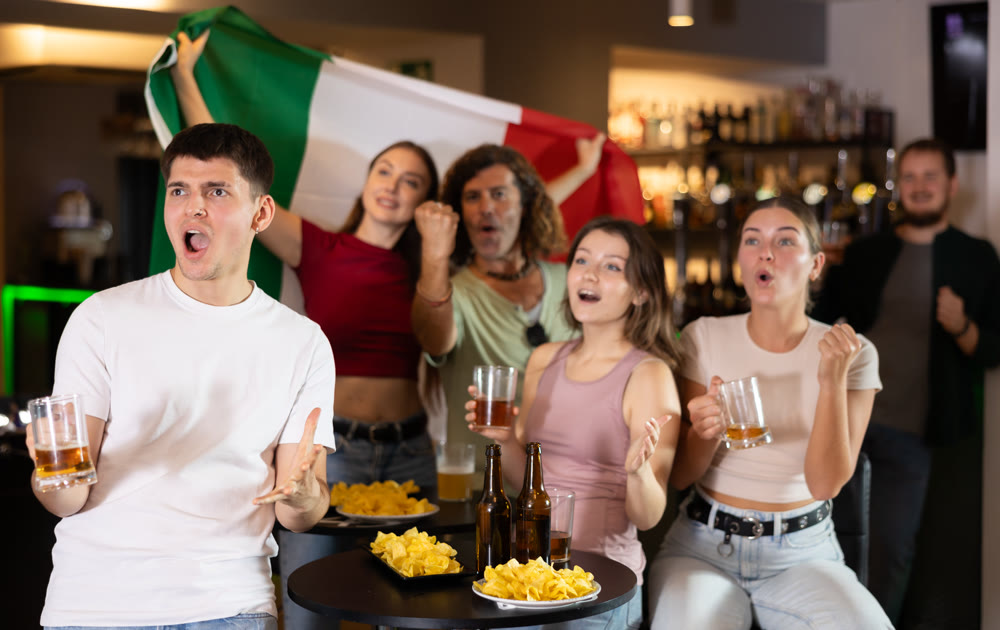 Italian fans with Italian flag emotionally watch the match on TV in pizzeria