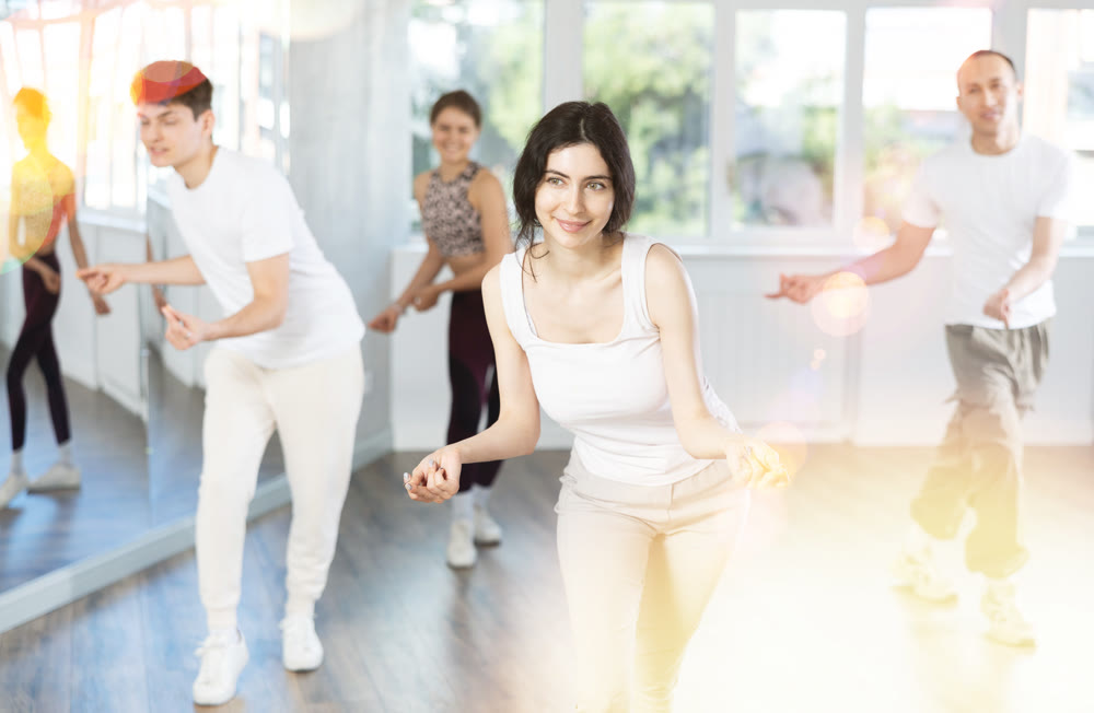 Group of happy young people enjoying a contemporary dancing class. Team of smiling dancers in casual wear practising new choreo