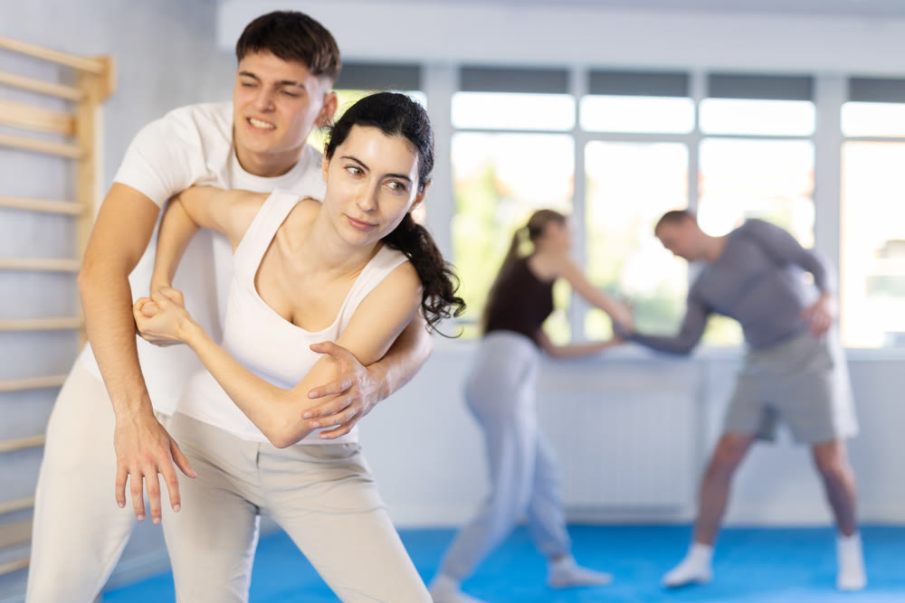 Young girl practicing self-defense techniques in pairs with guy