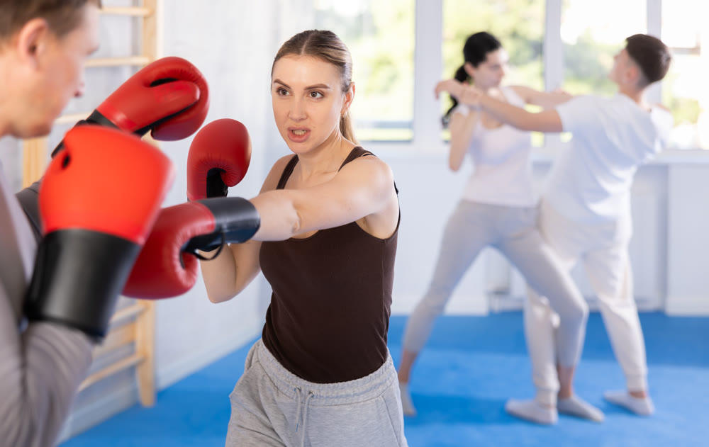 Girl in boxing gloves learns to box under the guidance of trainer in gym