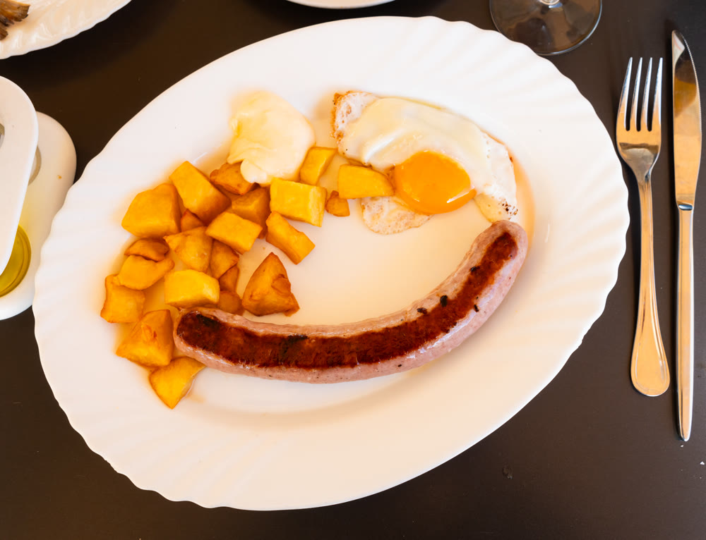 Fried egg and pieces of potato are complemented by butifarra sausage