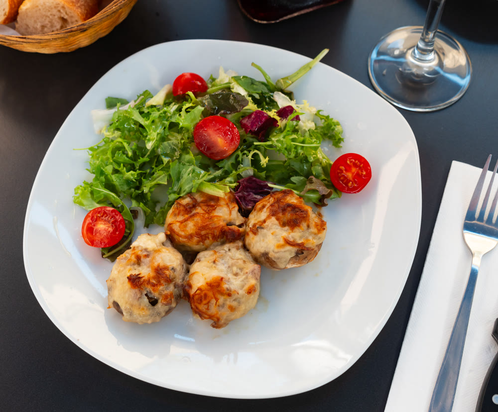 Stuffed champignons are baked under cheese topping.