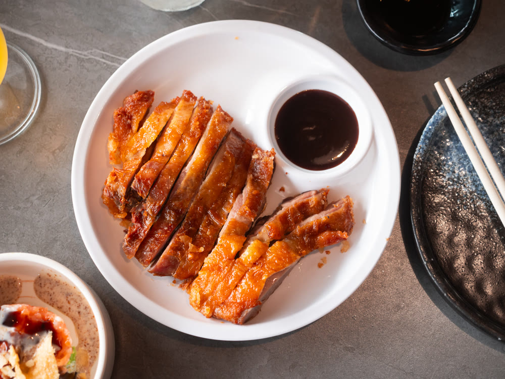Appetizing pieces of baked duck breast are served with spicy sauce and decorated with white sesame seeds