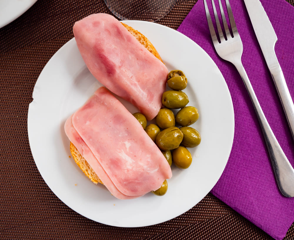 Ham sandwich and green olives on plate - an appetizing snack