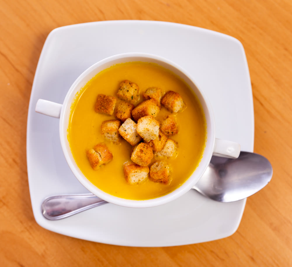 Plate is filled with homogeneous cream soup, dish made from seasonal vegetables and zucchini