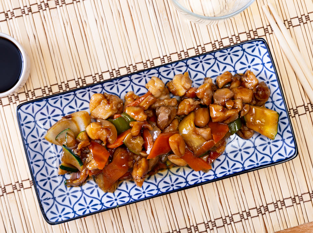 Chicken pieces in almond sauce with stewed eggplant and peppers closeup