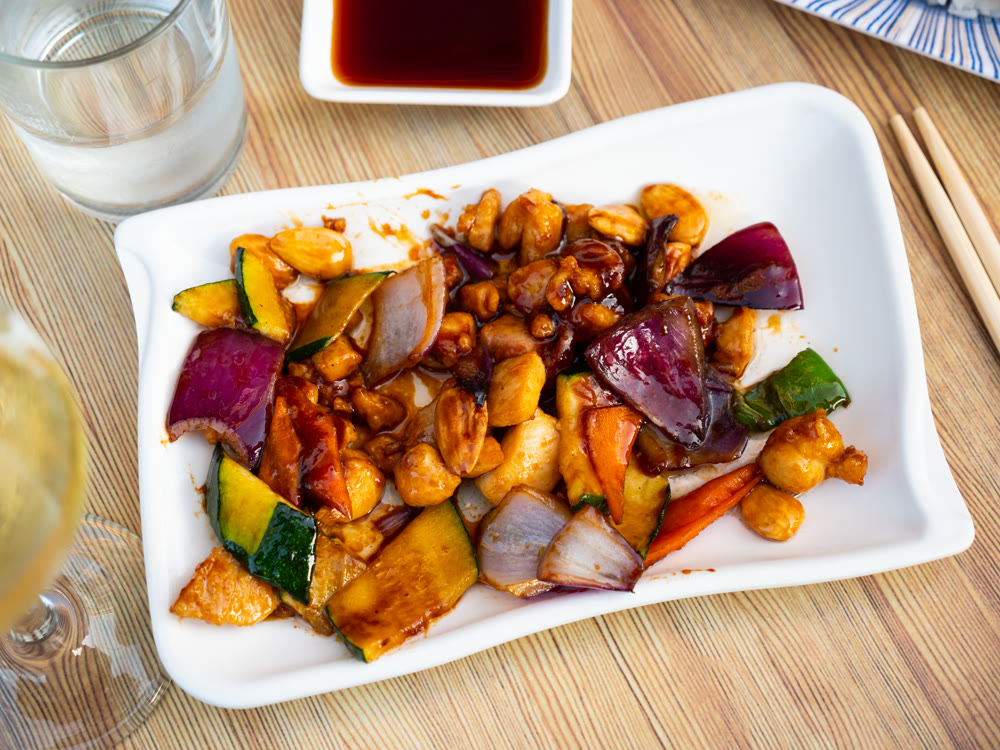 Baked or fried dish - chicken fillet, onion rings, pieces of vegetables, and whole almonds