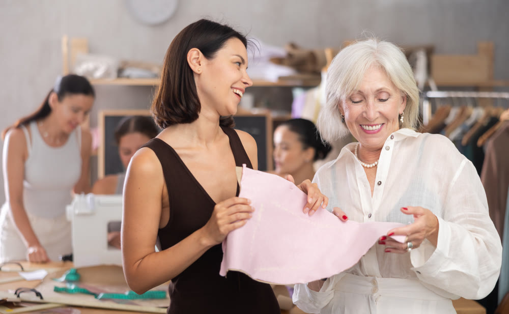 Young and elderly women discussing pattern at sewing master class