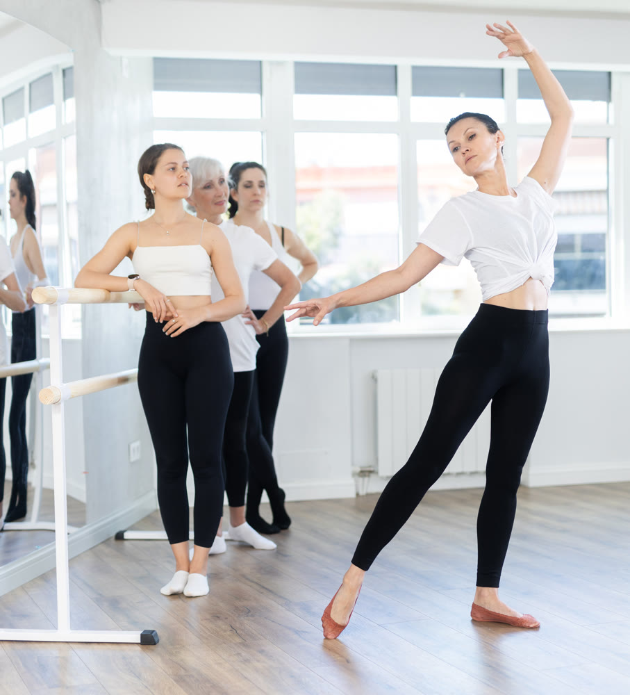 Female teacher leading ballet class, showing movements to group