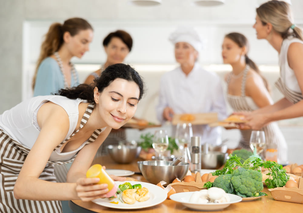 Young woman pouring sauce into dish at master class
