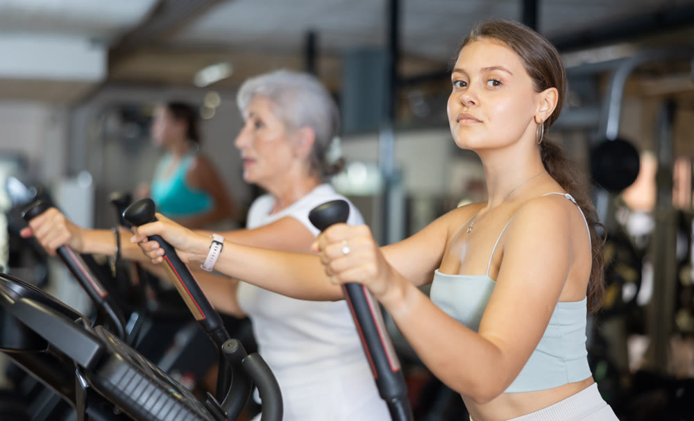 Portrait of sporty woman doing cardio workout on elliptical cross trainer at fitness center