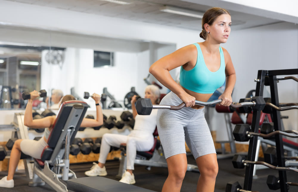 Portrait of a sporty girl doing exercises with dumbbells in gym