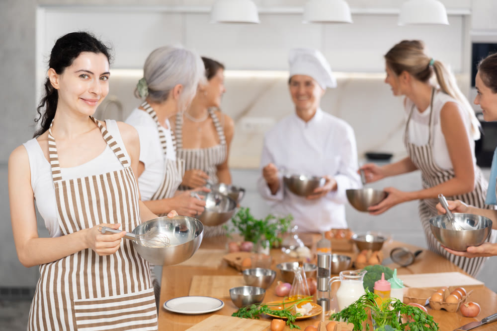 Girl while studying at culinary workshop, cooks appetizing sauce, marinade, dough in bowl.