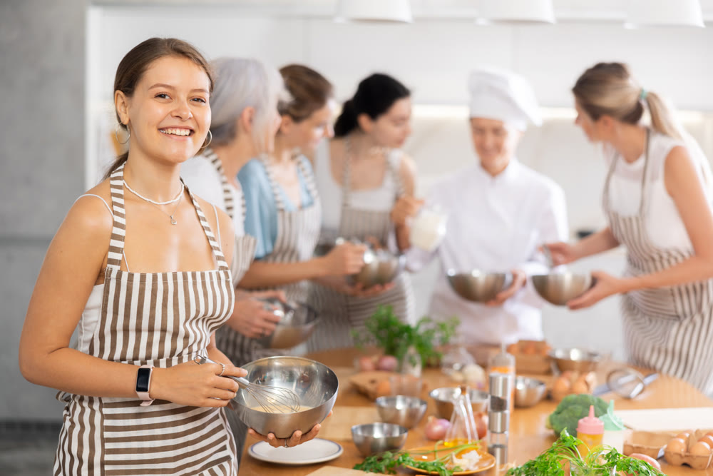 Girl while studying at culinary workshop, cooks appetizing sauce, marinade, dough in bowl.