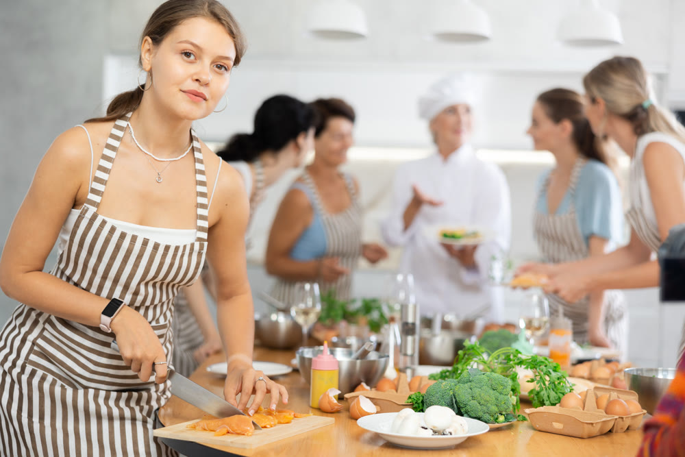 Young woman cutting raw chicken breast