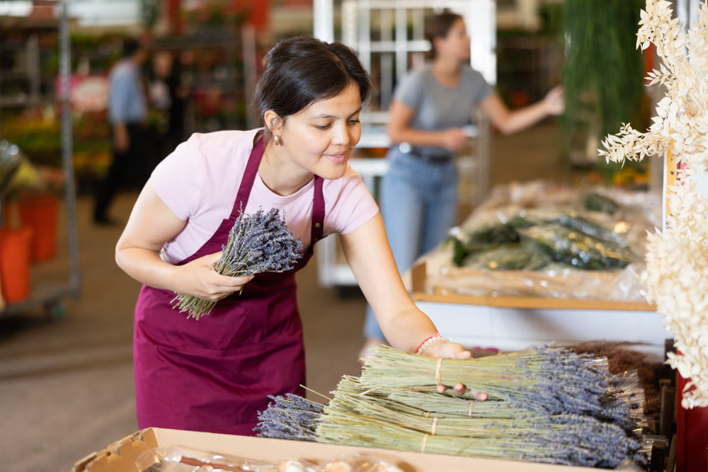 Girl florist chooses fresh lavender to make flower bouquet at flower market