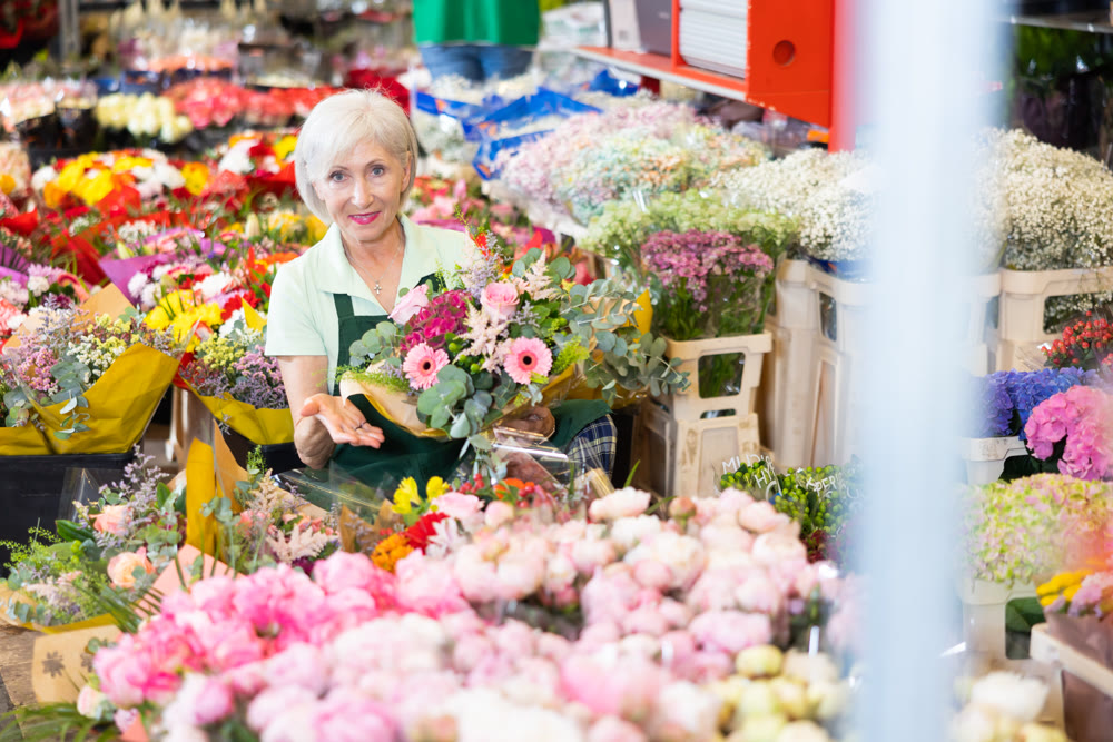 Portrait of happy hostess of flower market with bouquet in her hands