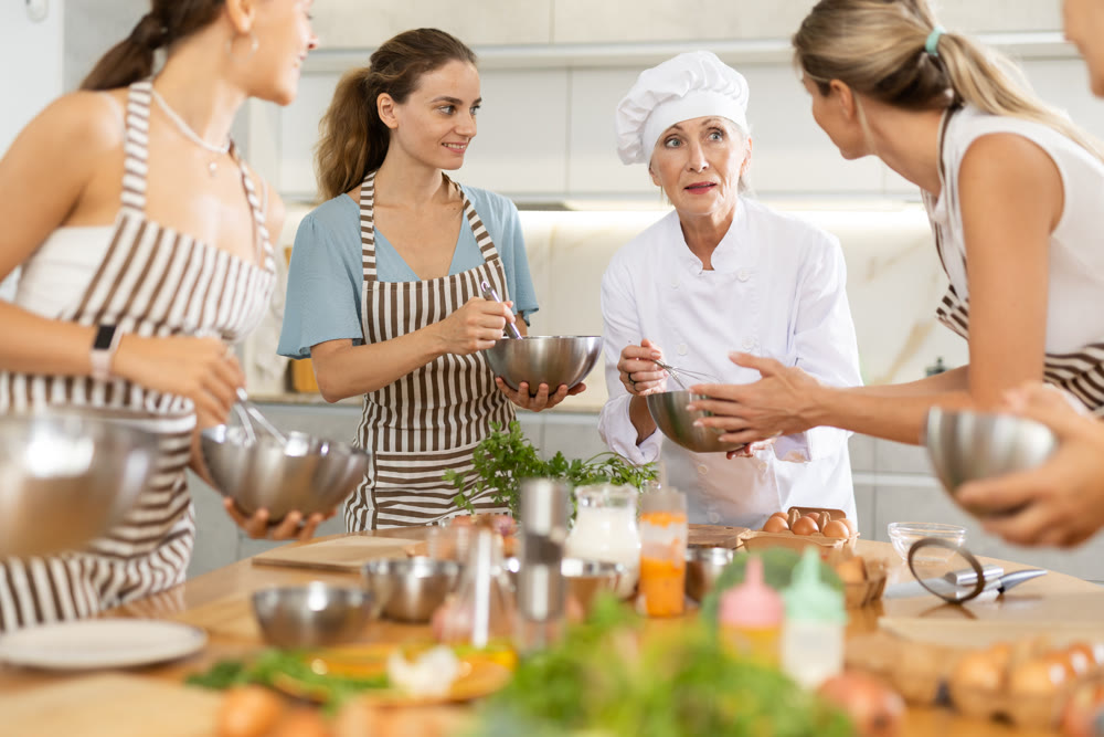 Elderly woman teaching cooking to group of woman