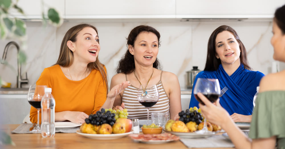 Happy women congregated around a festive table; participating in animated discussions and enjoying the delights of wine