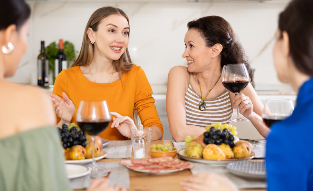 Happy women congregated around a festive table; participating in animated discussions and enjoying the delights of wine