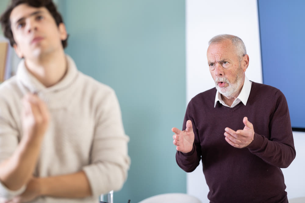 Elderly man scolds young man in office