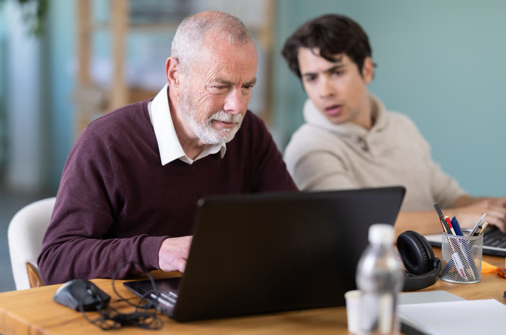 Two male manager work on laptops in modern company office