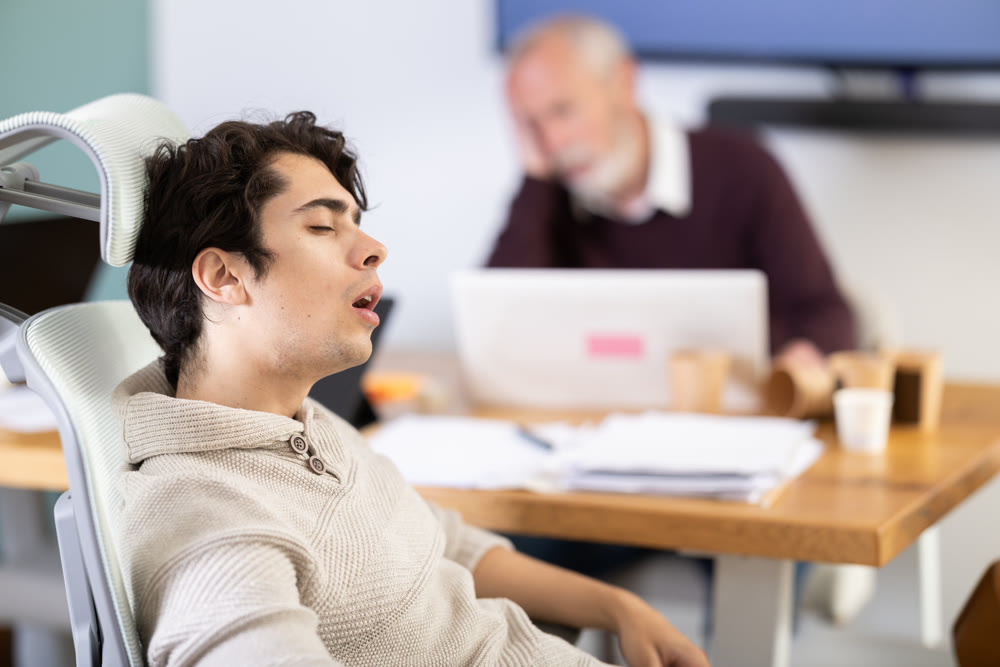 Wearied senior man and guy colleagues are dozing near workplace in office