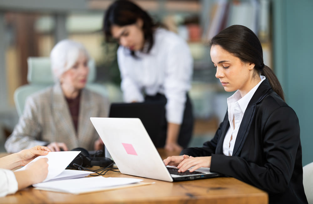 Young woman working on laptop during busy corporate session