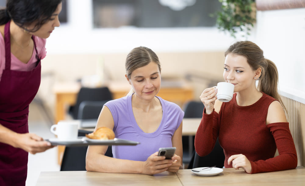 Friendly waitress brought croissants and coffee to female customers