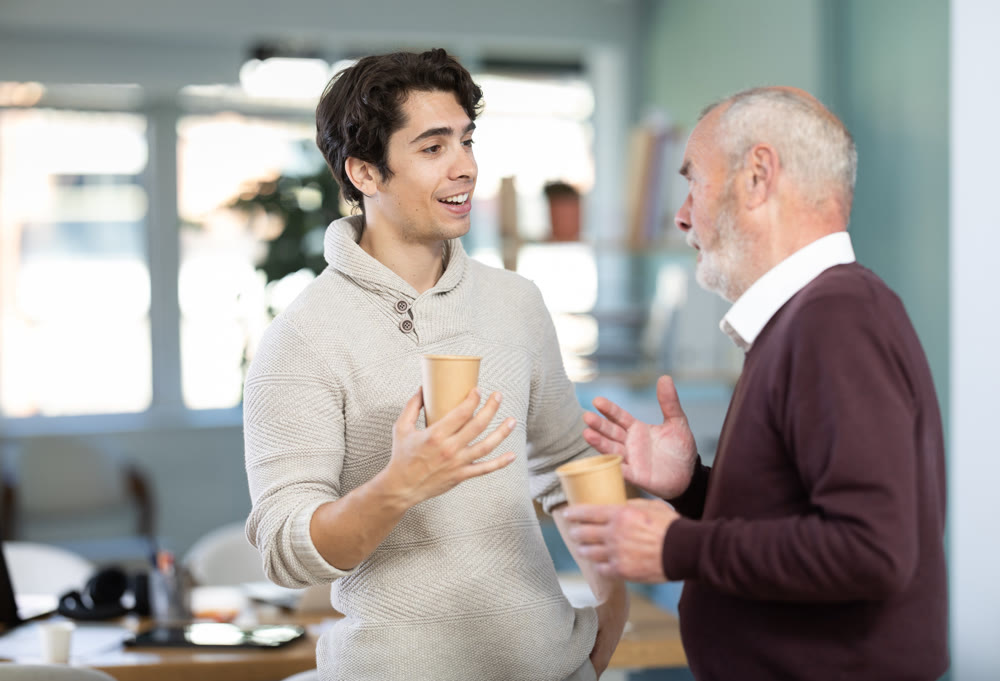Two office workers drink coffee and chat during work break