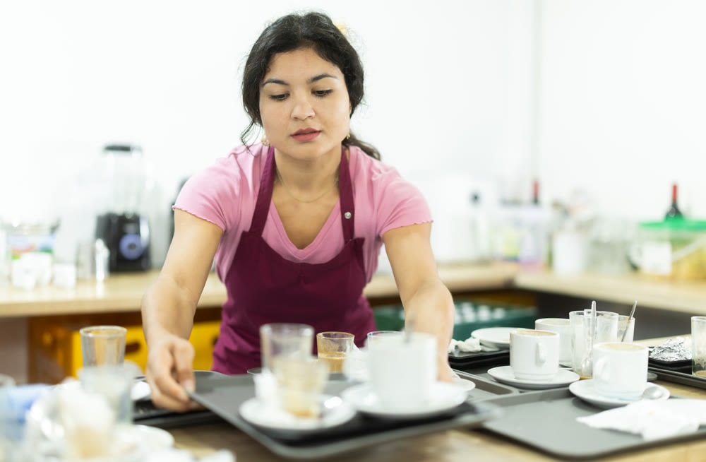 Young woman waitress collects dirty dishes