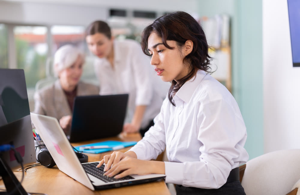 Focused young woman working on laptop during busy corporate session
