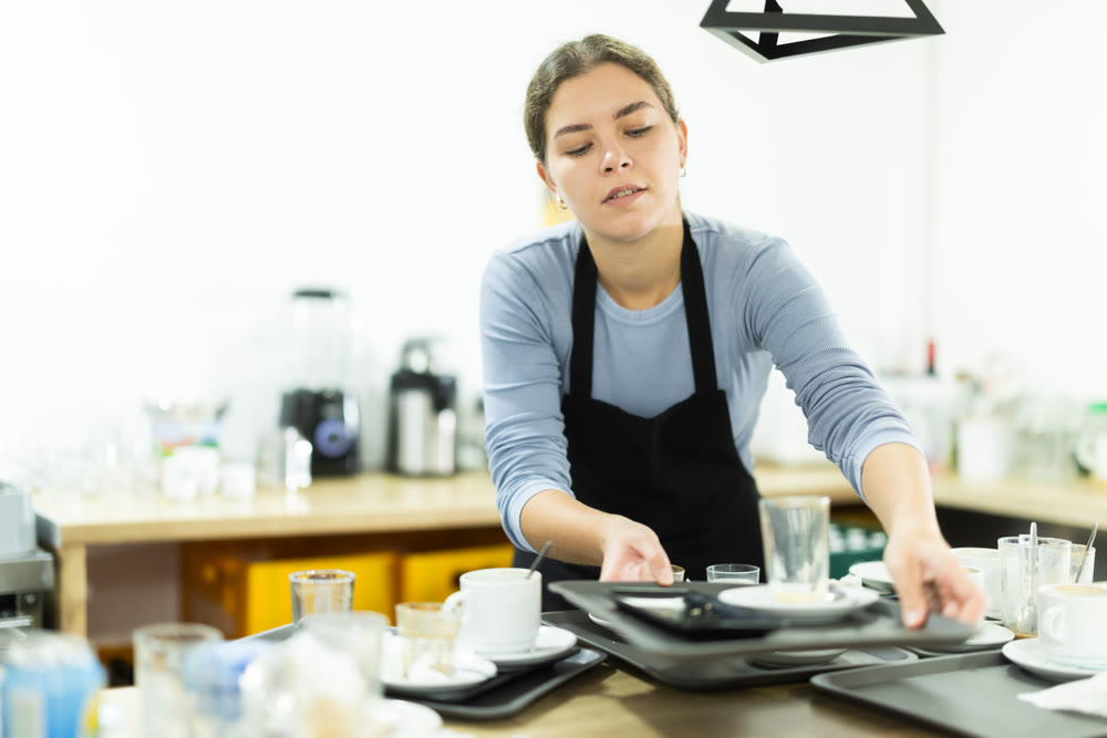 Waitress taking away dirty dish in cafeteria