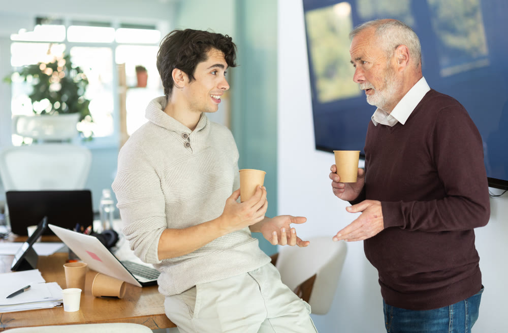 Young and elderly men colleagues drinking coffee in office