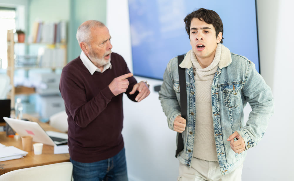 Mature boss scolds an male employee for being late for work