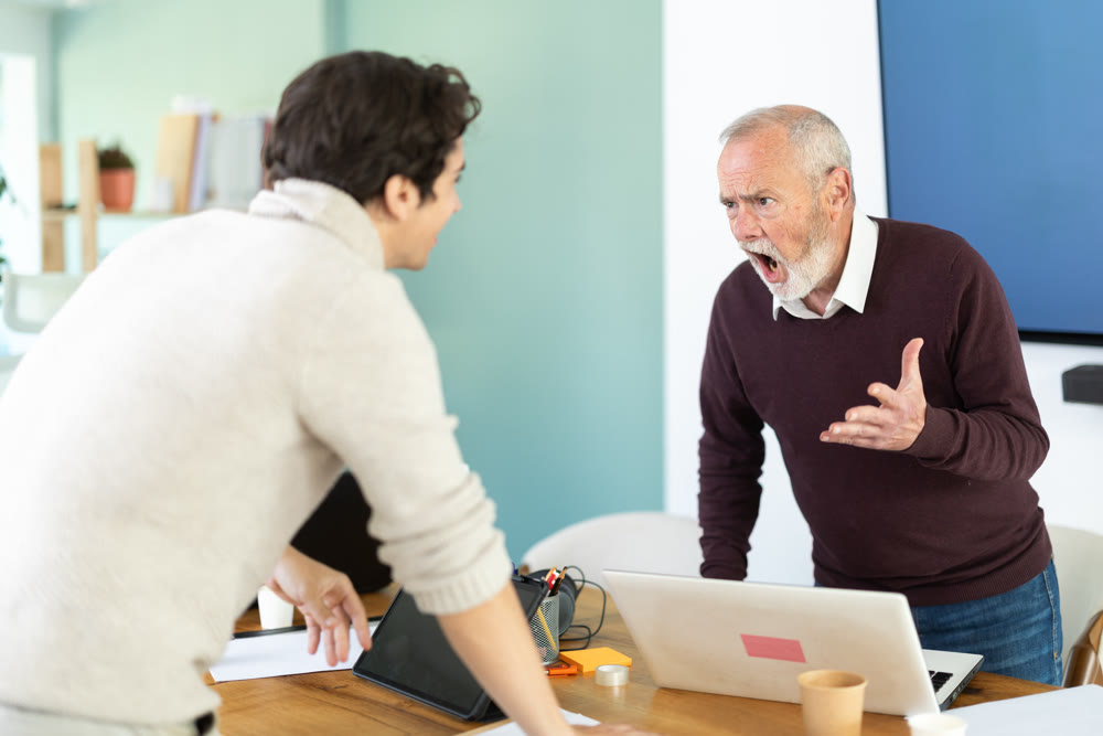 Elderly and young male colleague are arguing excitedly in office