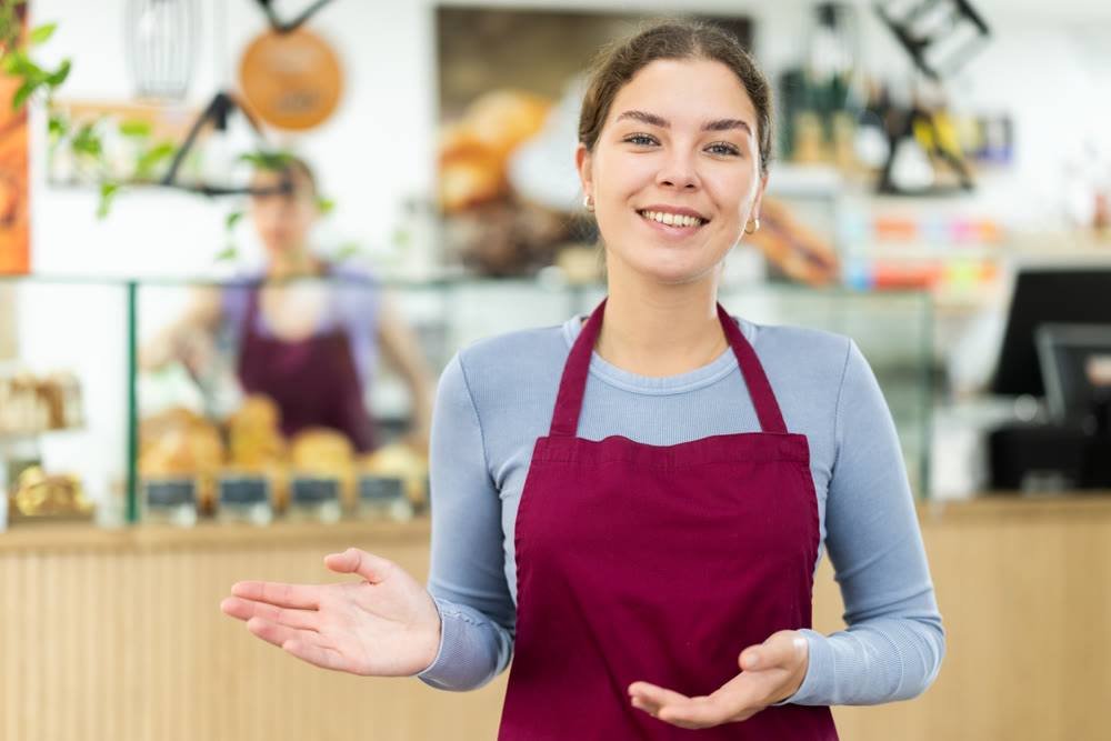 Female cafe employee greets guests of establishment