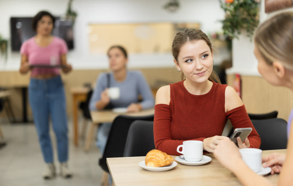 In cafe, girl chatting sweetly during tea party with girl buddy