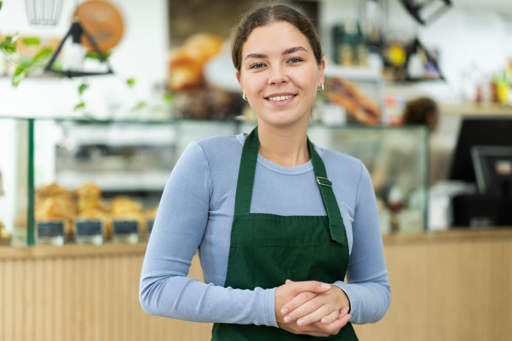 Female cafe employee greets guests of establishment