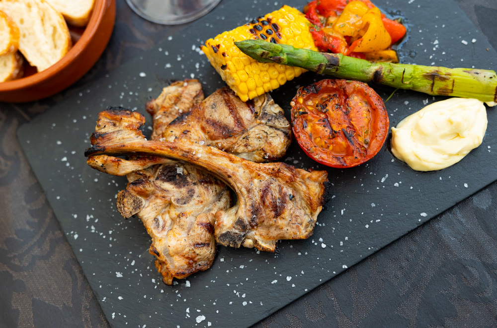 Lamb chops on ribs with grilled corn, tomato, sweet pepper and asparagus