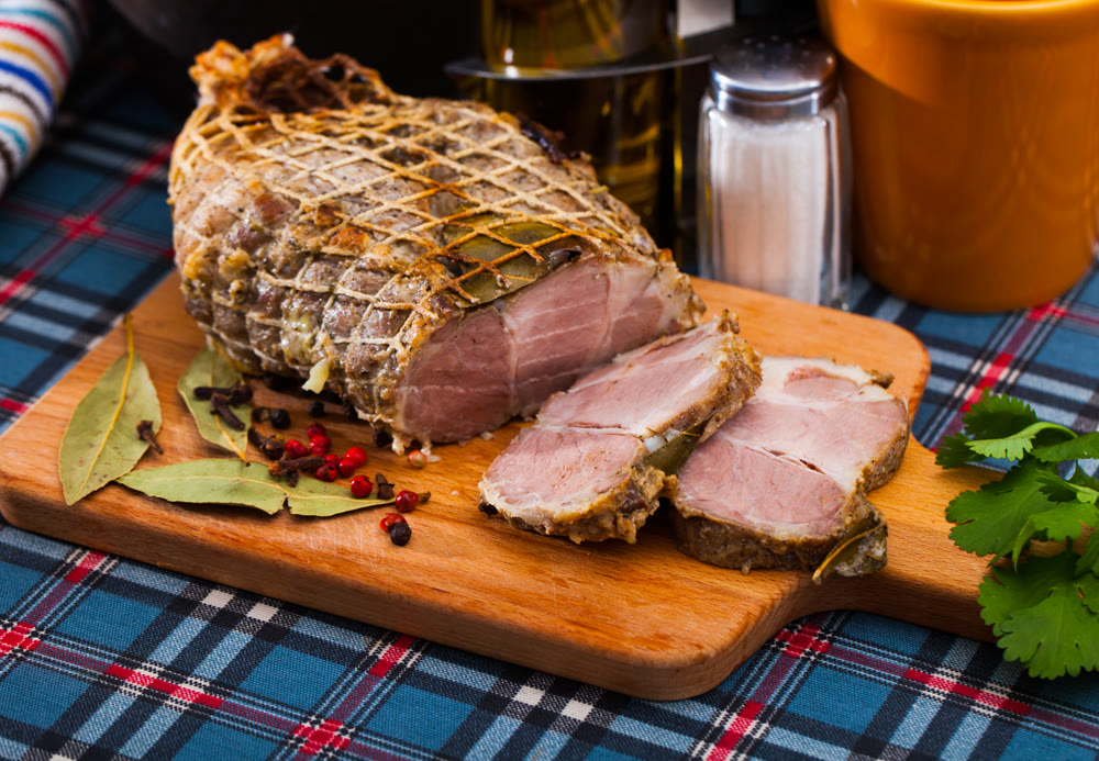 Boiled pork on chopping board with mixed peppercorns, bay leaf, cinnamon