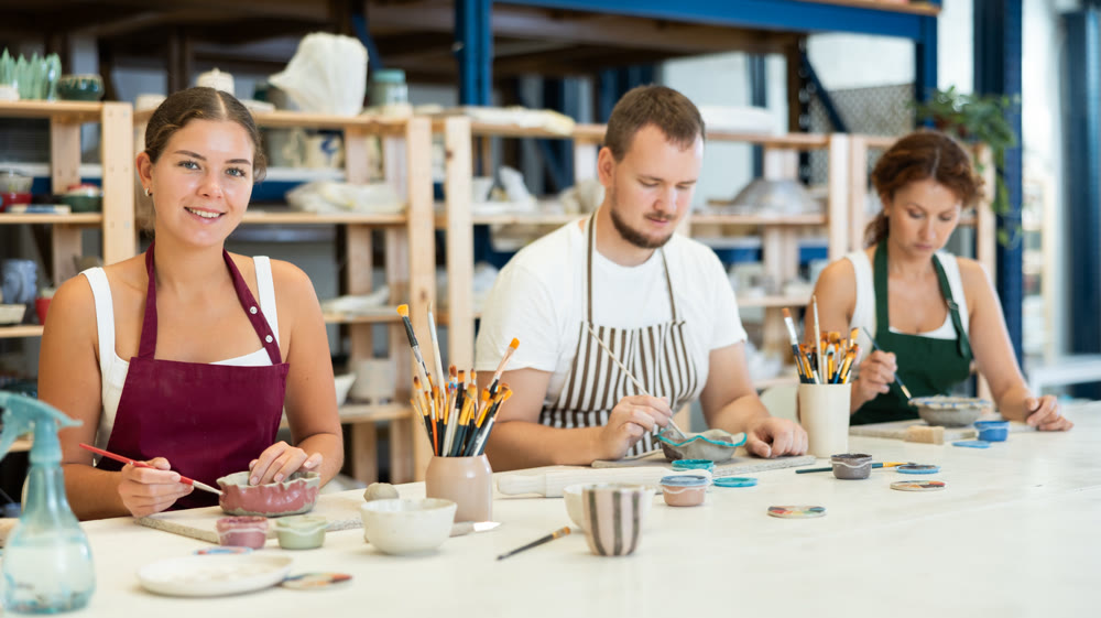 Three craftsperson are busy painting clay products