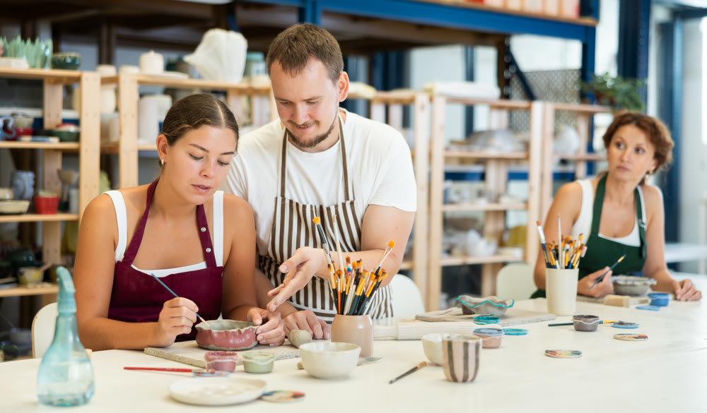 Male potter explains to students how to shape clay to make beautiful ceramic dishes