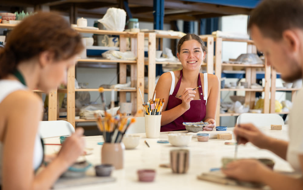Pottery workers paint ceramic plates together at table
