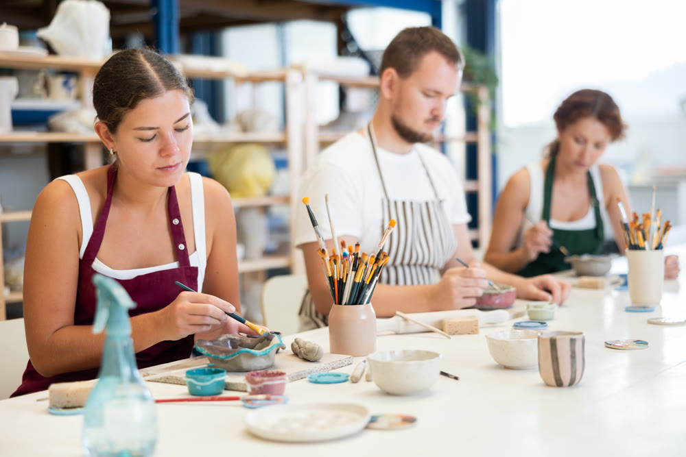 Three craftsperson are busy painting clay products